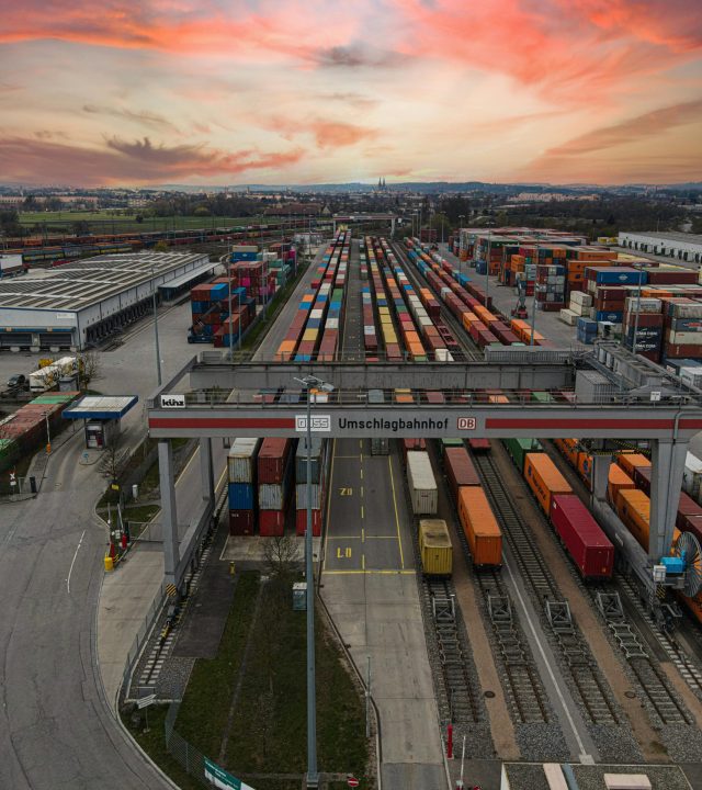 Aerial view of a bustling shipping yard with colorful containers at sunset, highlighting logistics.